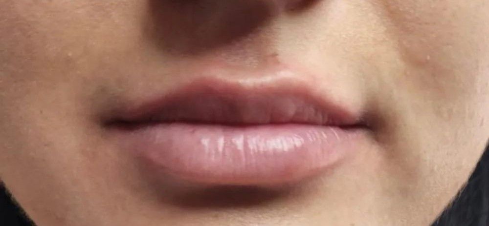 Close-up of a person's lips. The lips are full, slightly parted, with a natural, light pink color.