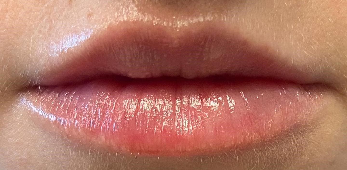 Close-up of glossy lips, pinkish-red color.