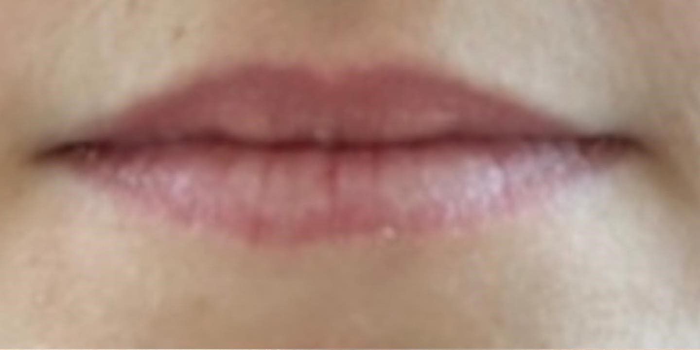 Close-up of a person's lips. The lips are closed and a natural pink color, with subtle texture visible.