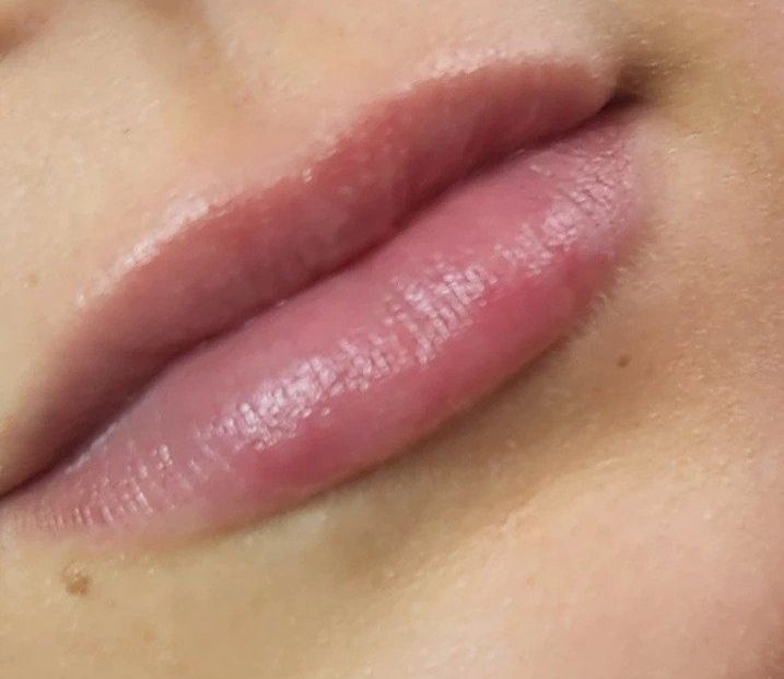 Close-up of a person's slightly parted, full lips, glossy and pinkish-red in color.