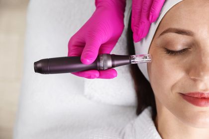 Gloved hand uses a pen-style cosmetic tool near a woman’s face as she lies with eyes closed