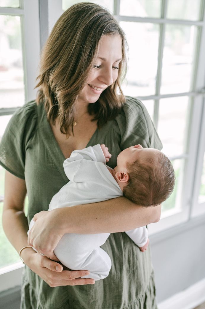 Morgan Farkas, Waukesha birth and postpartum doula holding a newborn baby while smiling
