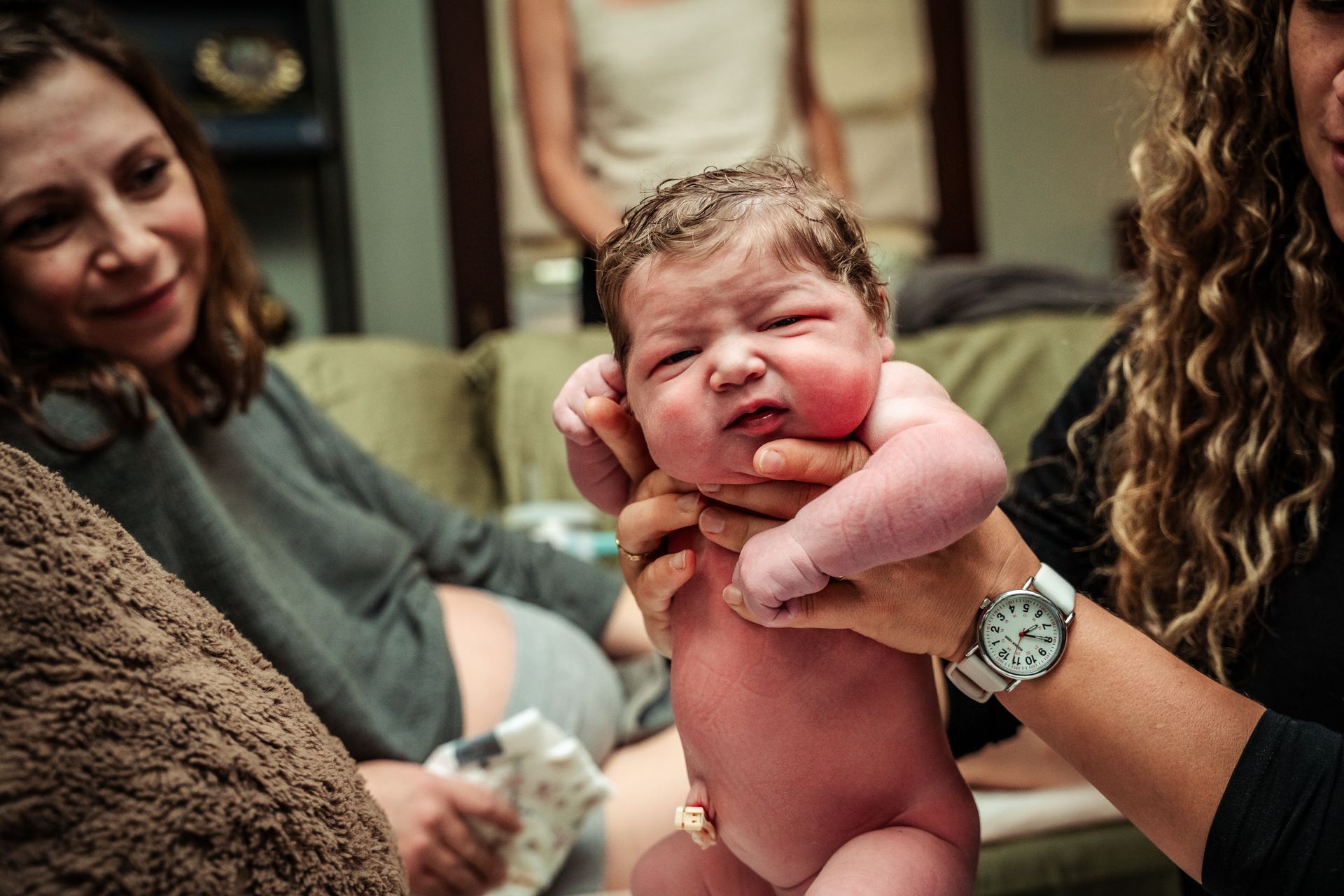 newborn baby born at home doing the newborn exam while mom watches