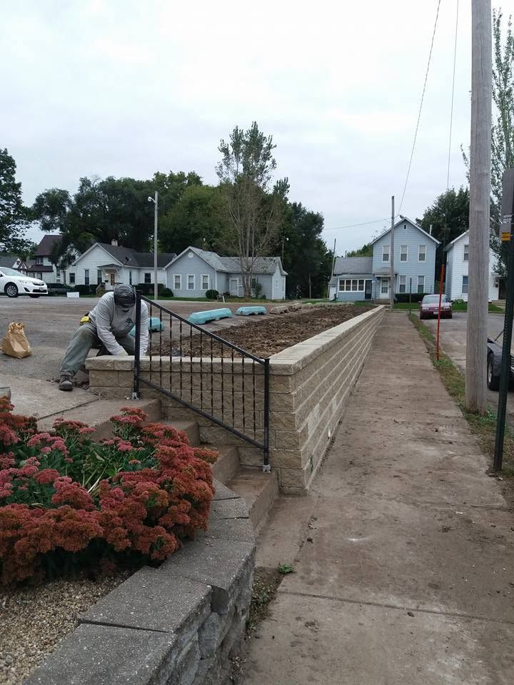 Worker smoothing concrete for a low brick wall in a residential neighborhood
