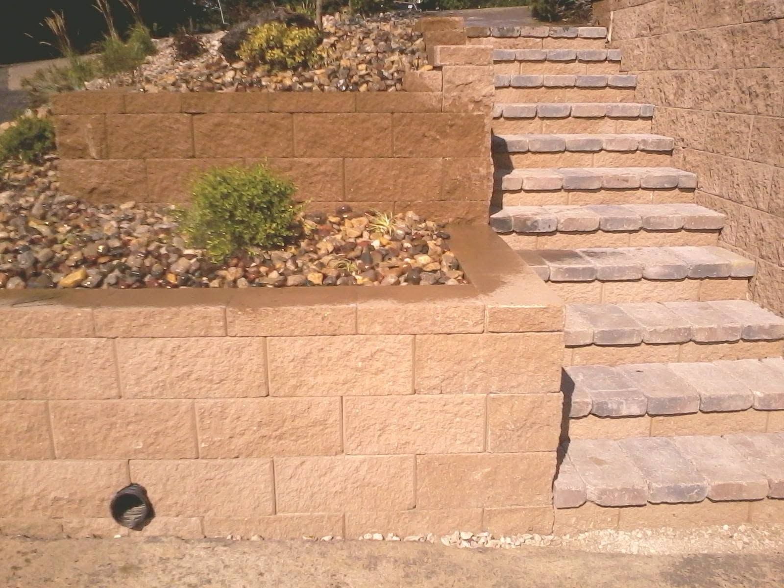 Landscaped retaining wall with stone steps leading up a slope