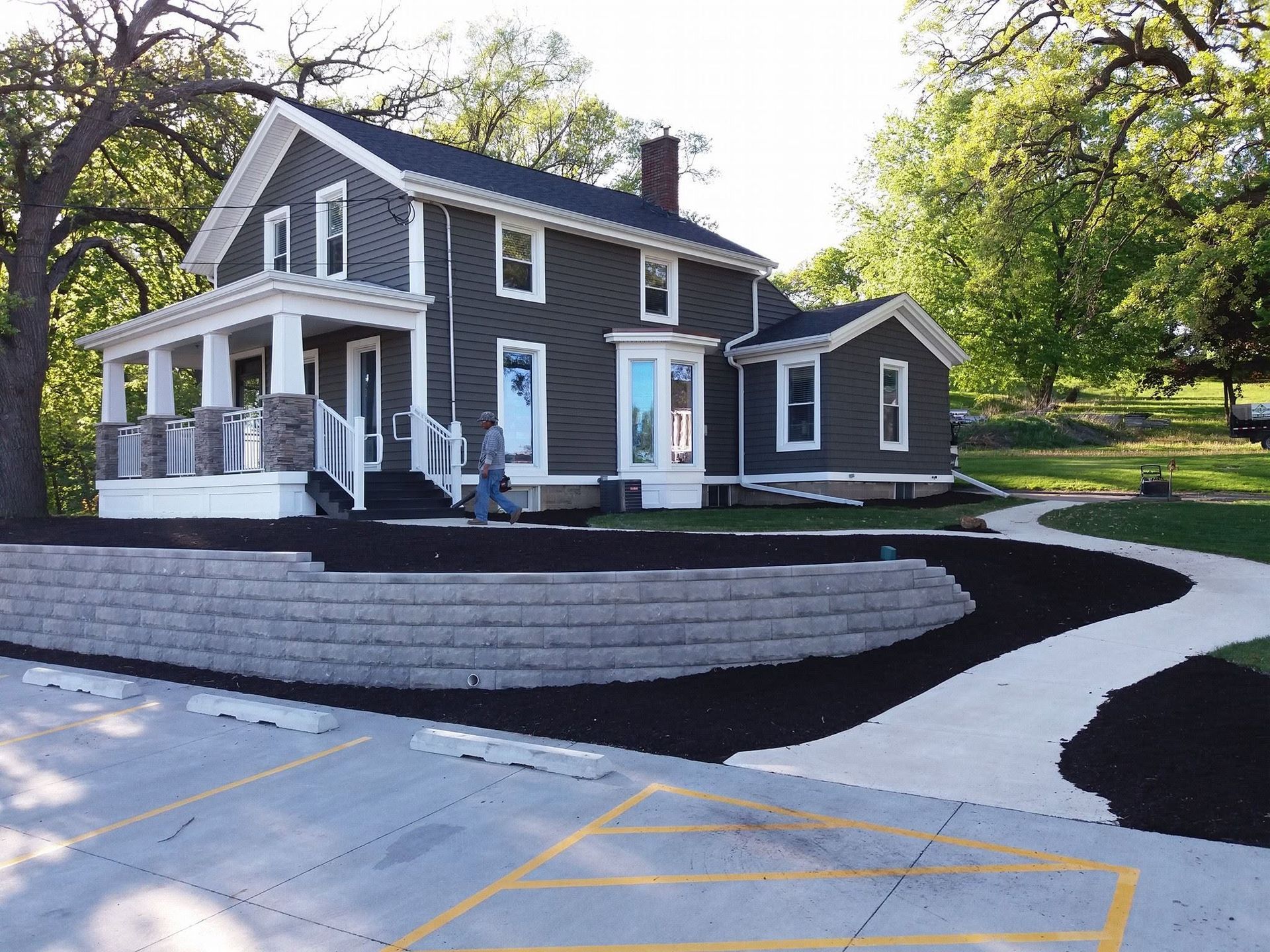 Gray two-story house with white trim and porch, curved walkway, and landscaped front yard at dusk