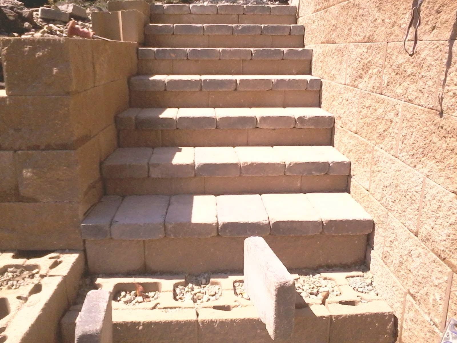 Stone steps outdoors leading upward beside tan masonry walls in bright sunlight