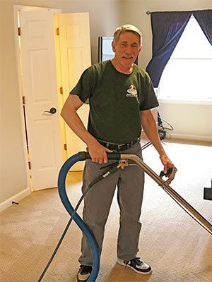 A man is standing in a room holding a vacuum cleaner.