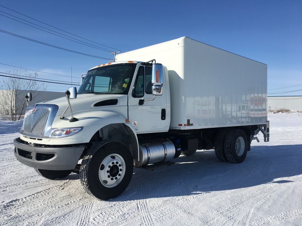 A white box truck is parked in the snow.