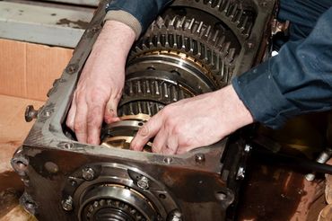 A man is working on a gearbox with his hands.