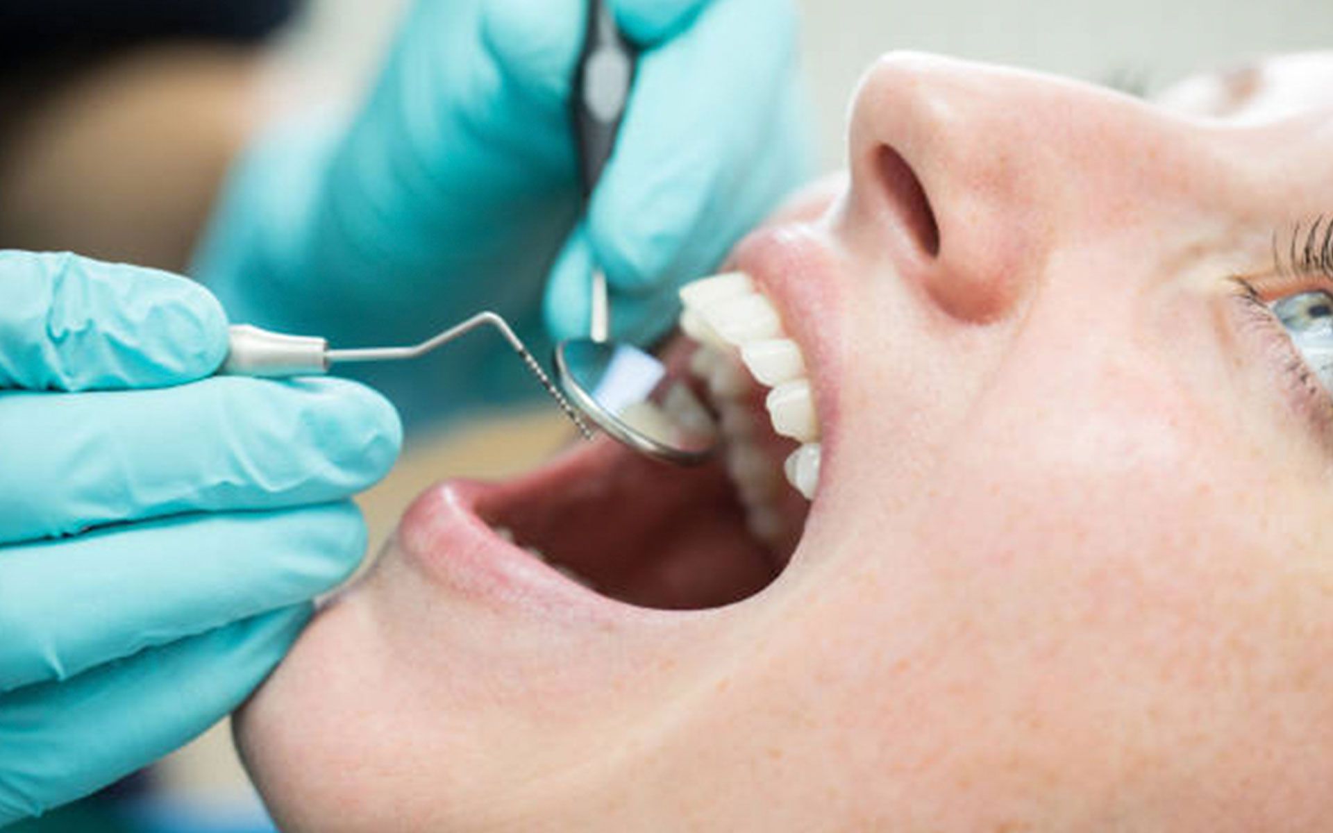 A woman is getting her teeth examined by a dentist.