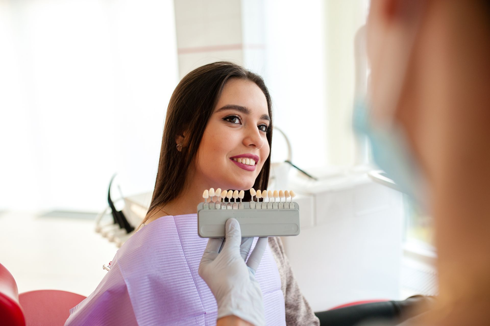 A dentist is using a porcelain shade guide on a patient.