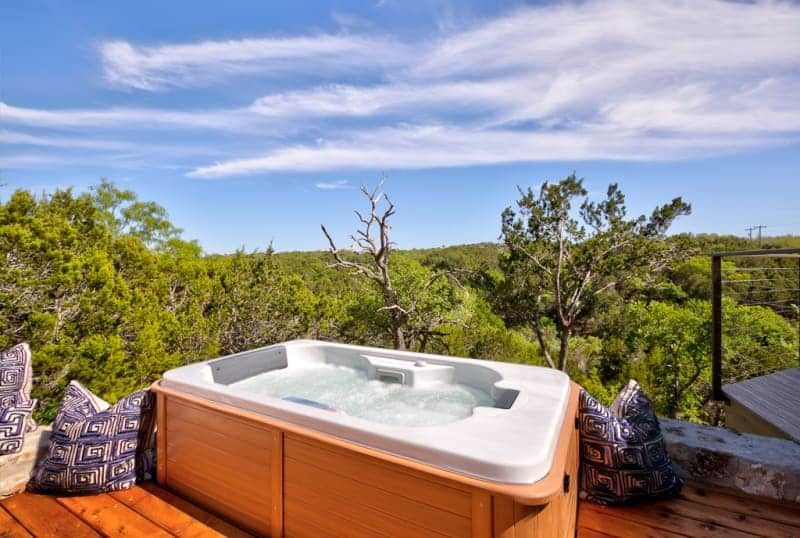 A hot tub is sitting on a wooden deck overlooking a forest.