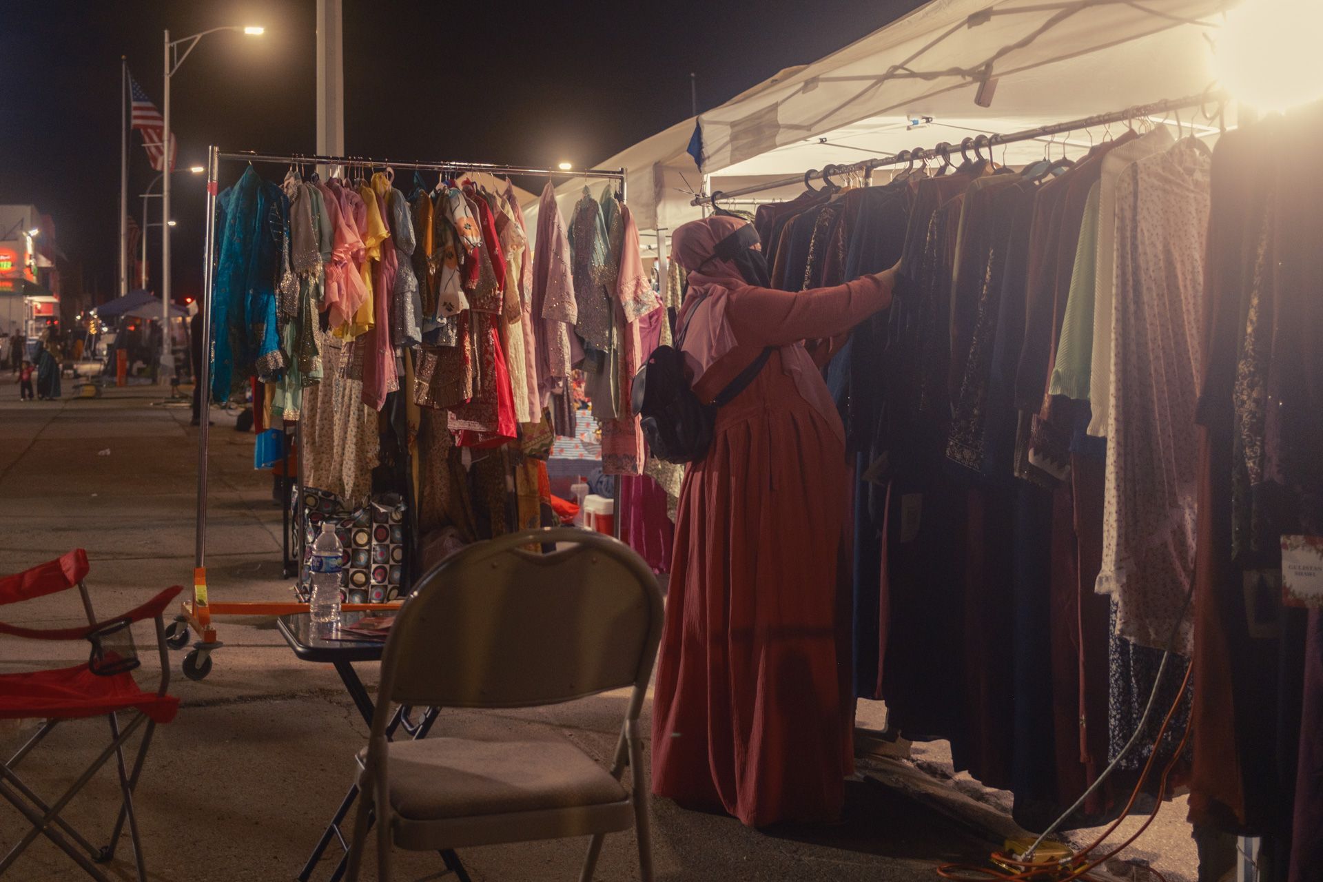Woman browsing colorful clothing at a nighttime street festival in Detroit, Michigan.