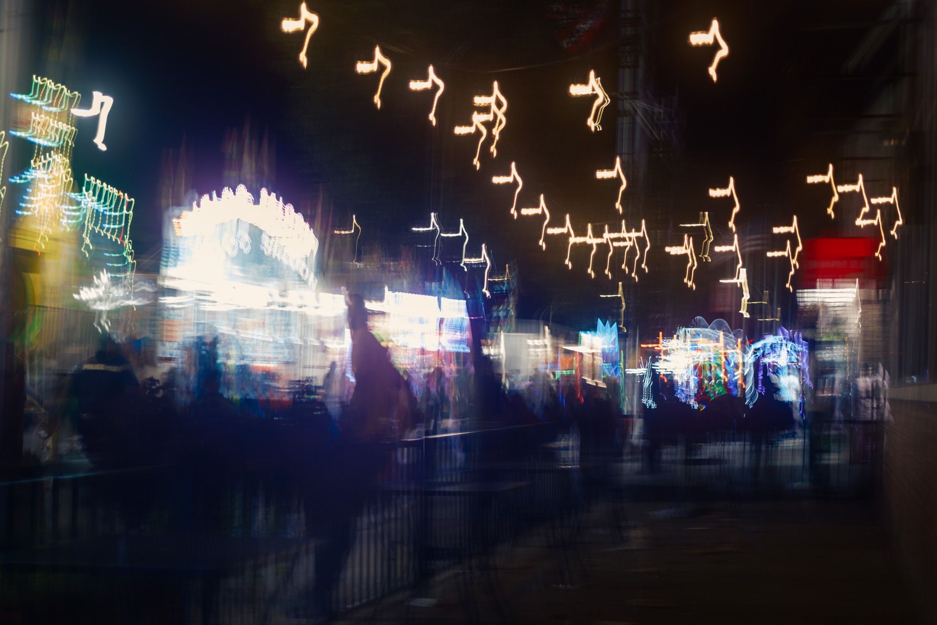 ICM style image of a bustling street fair at night with deliberate motion blur