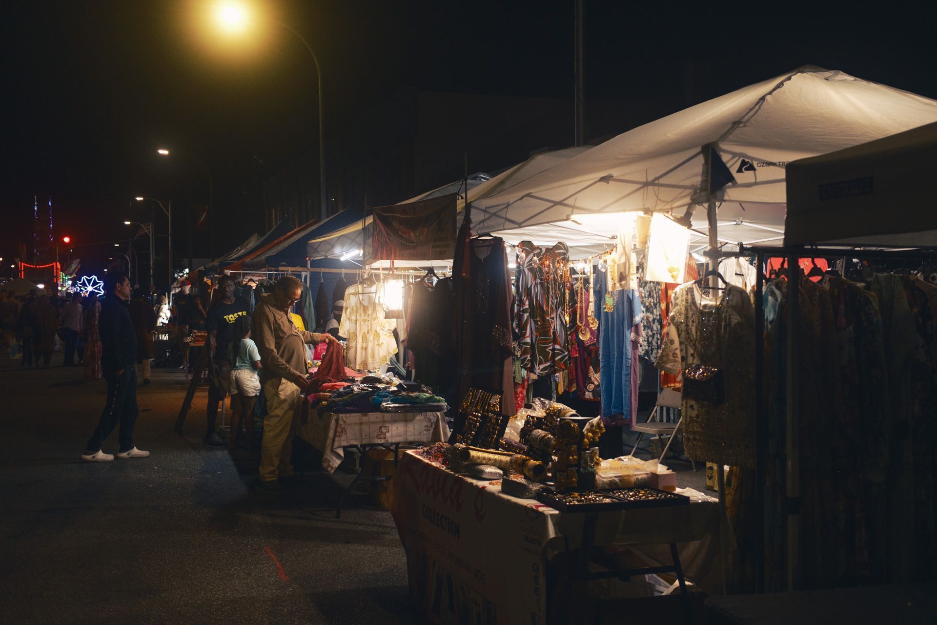 Man examines clothing at a night market in Detroit.
