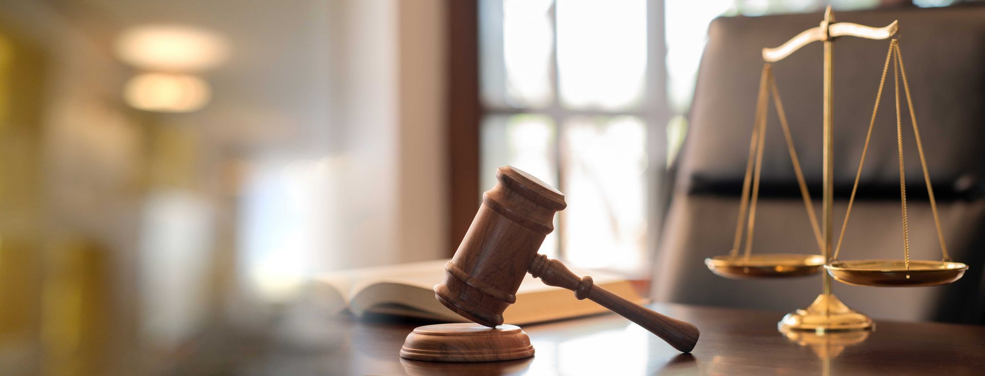Un maillet en bois et une balance sur un bureau, symbolisant le droit et la justice.