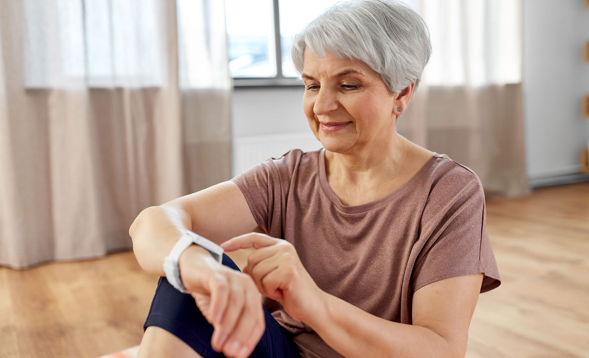 An elderly woman is wearing a smart watch on her wrist.