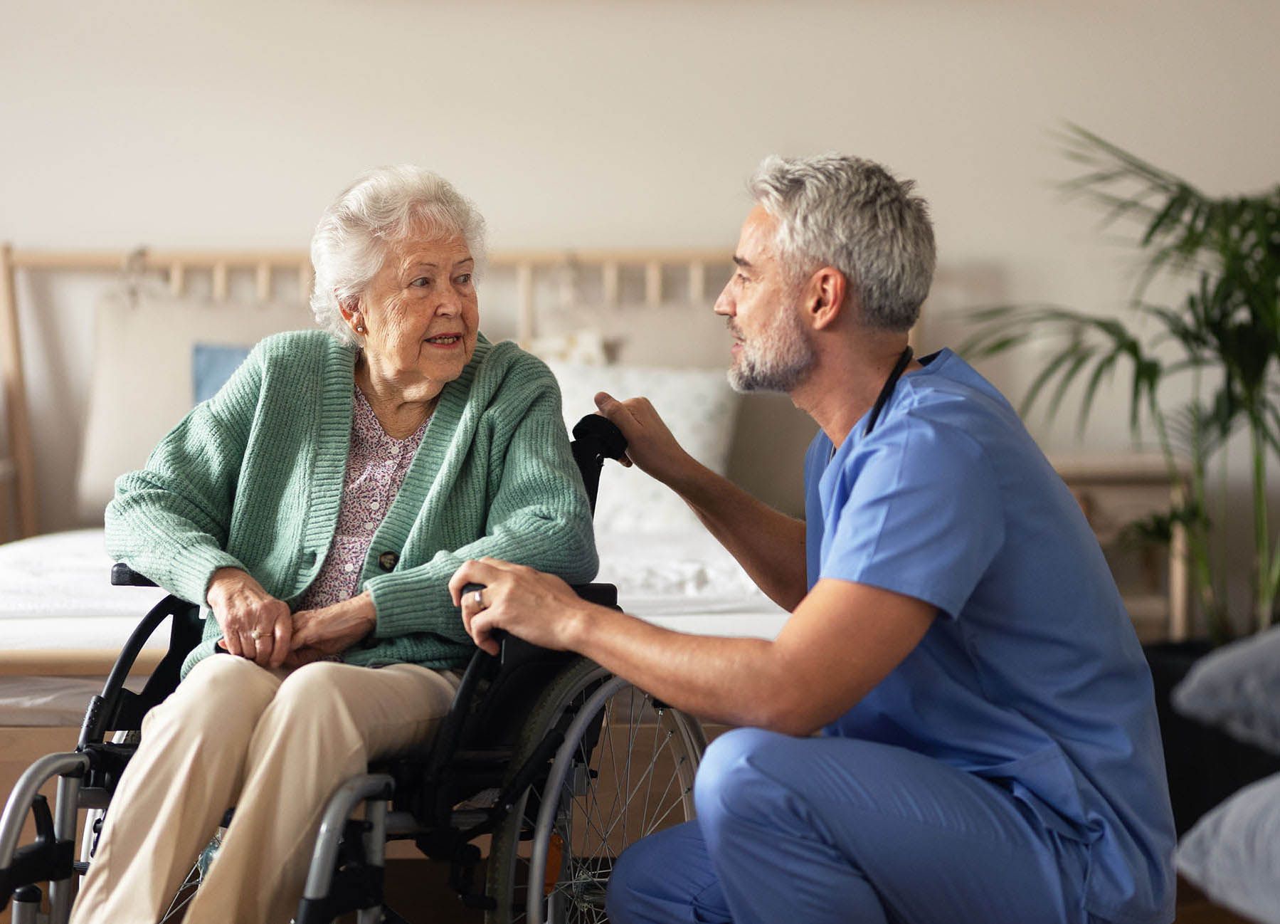 A nurse is talking to an elderly woman in a wheelchair.
