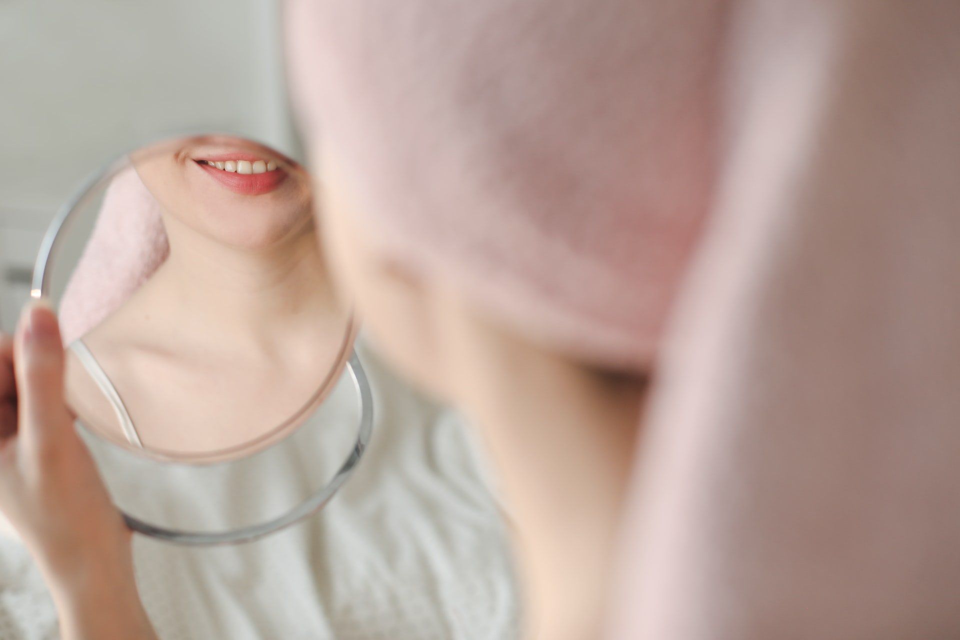 Woman looking into a hand-held mirror