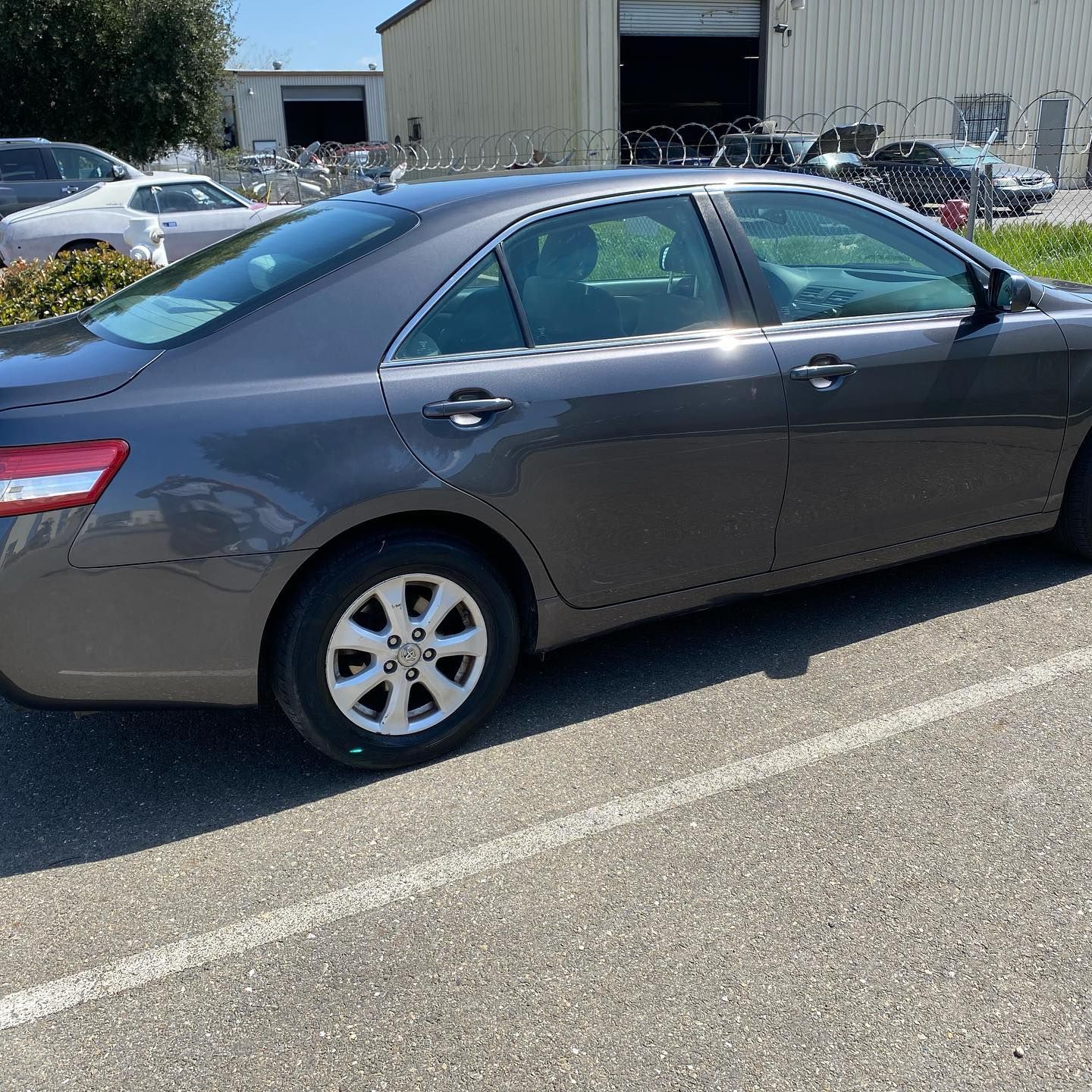 A gray car is parked in a parking lot in front of a building.