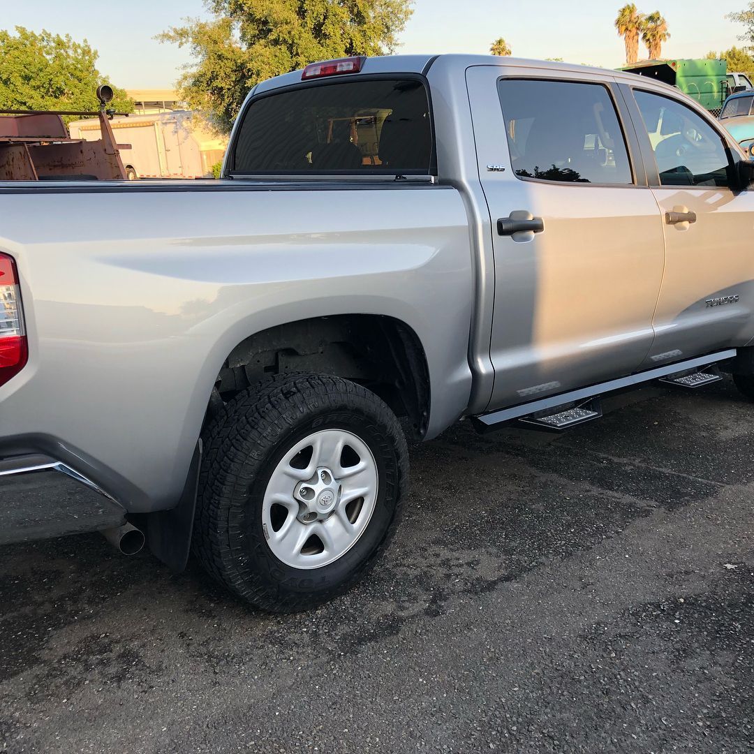 A silver truck is parked on the side of the road.