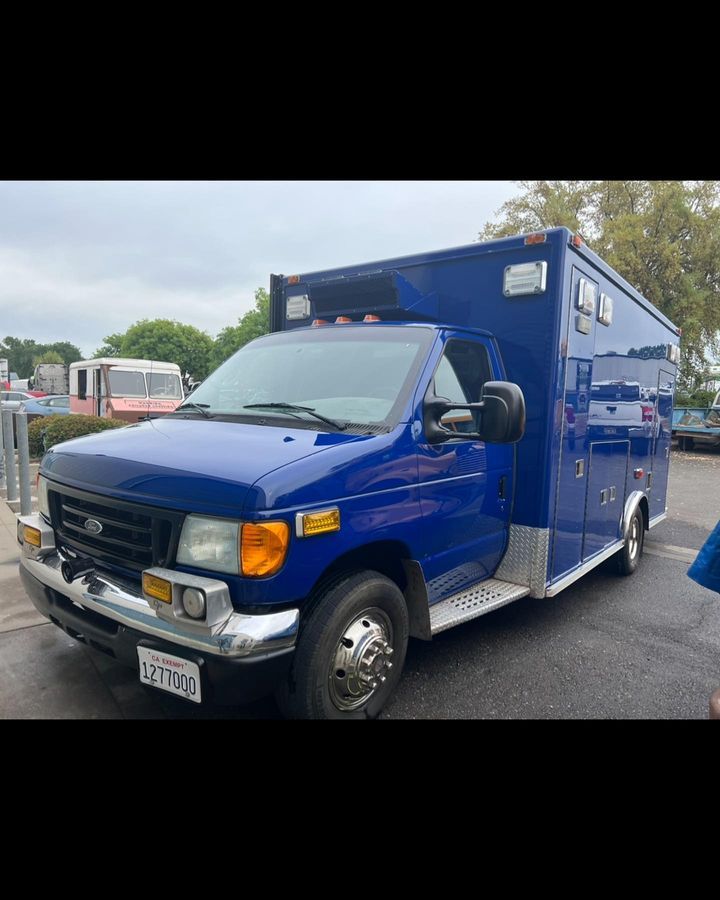 A blue ambulance is parked in a parking lot.