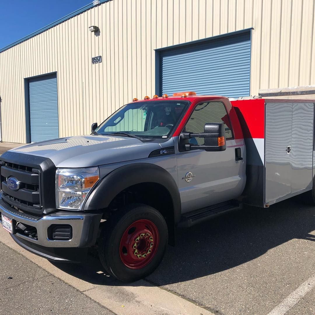 A silver truck with a red and white trailer is parked in front of a building.