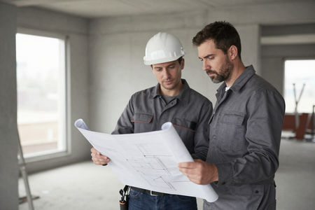 Contractor reviewing blueprints on active job site