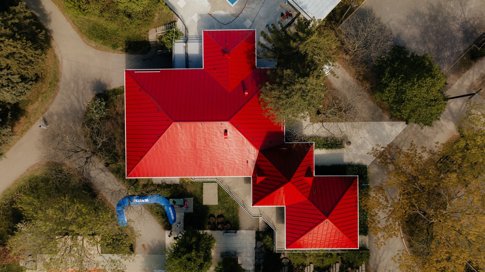 Une vue aérienne d'une maison au toit rouge entourée d'arbres.