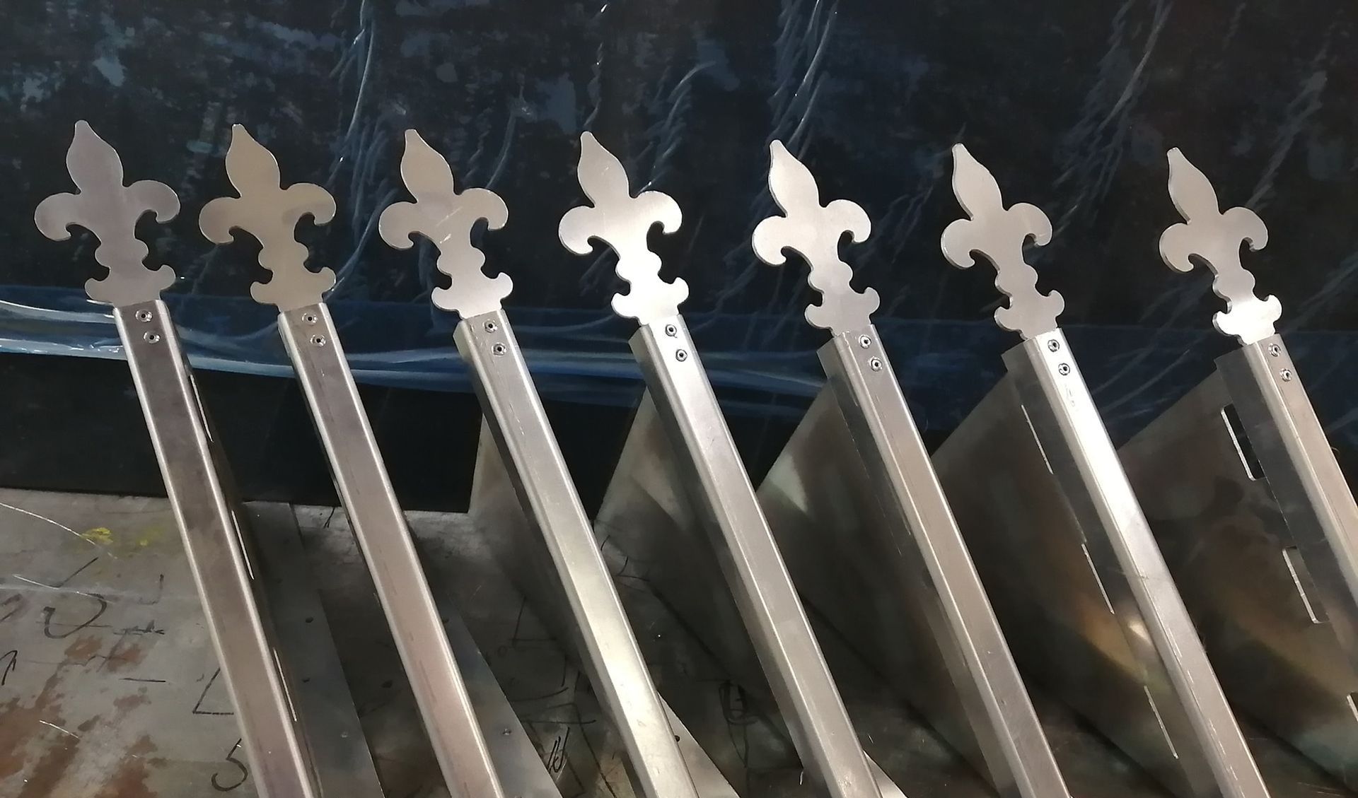 Une rangée de bâtons métalliques avec des motifs de fleurs de lys dessus