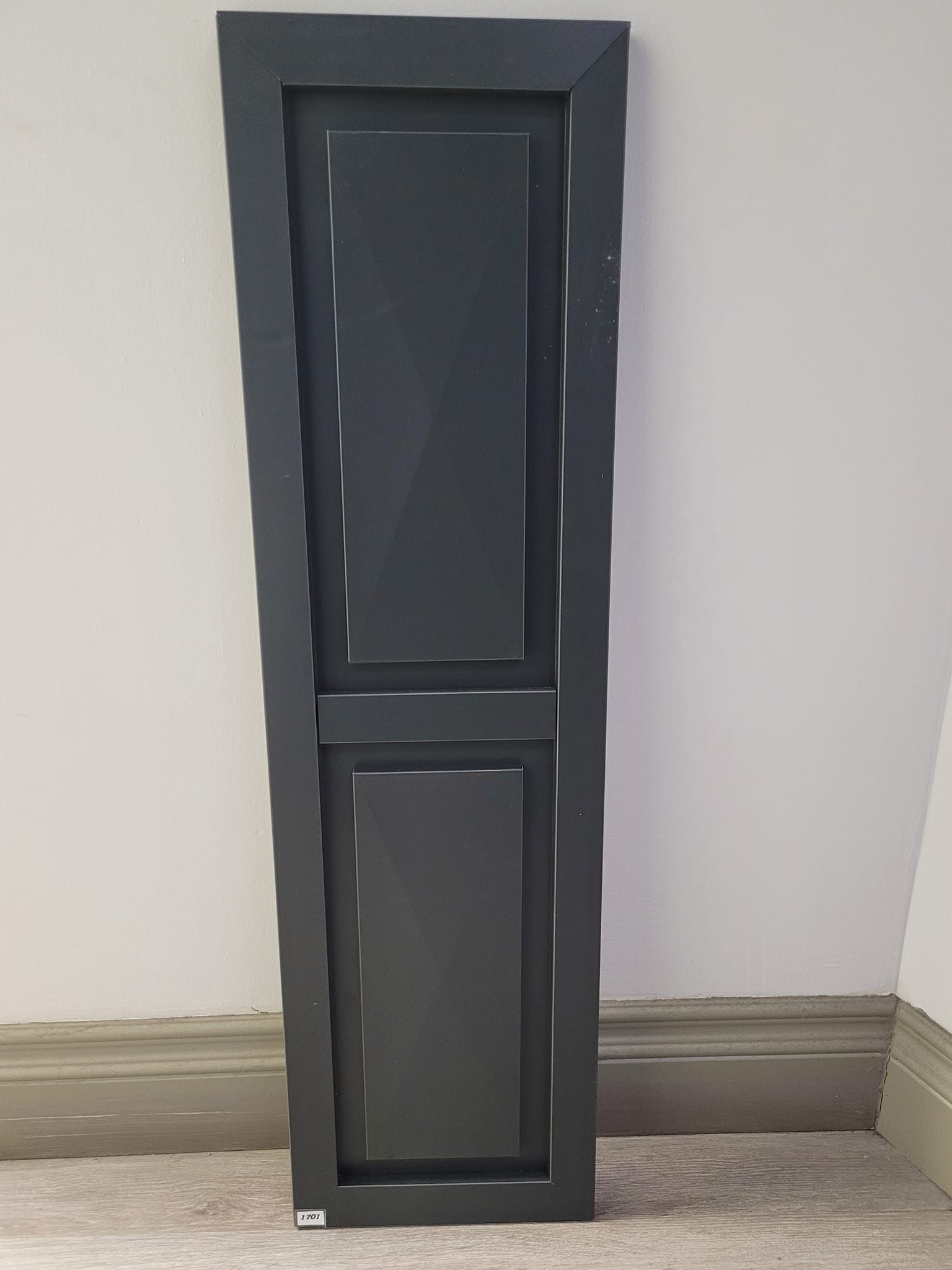 Une porte noire est posée sur un tapis à côté d'un mur.