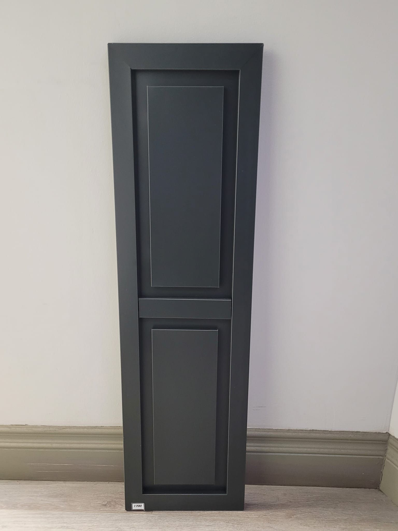 Une porte noire est posée sur un tapis à côté d'un mur.