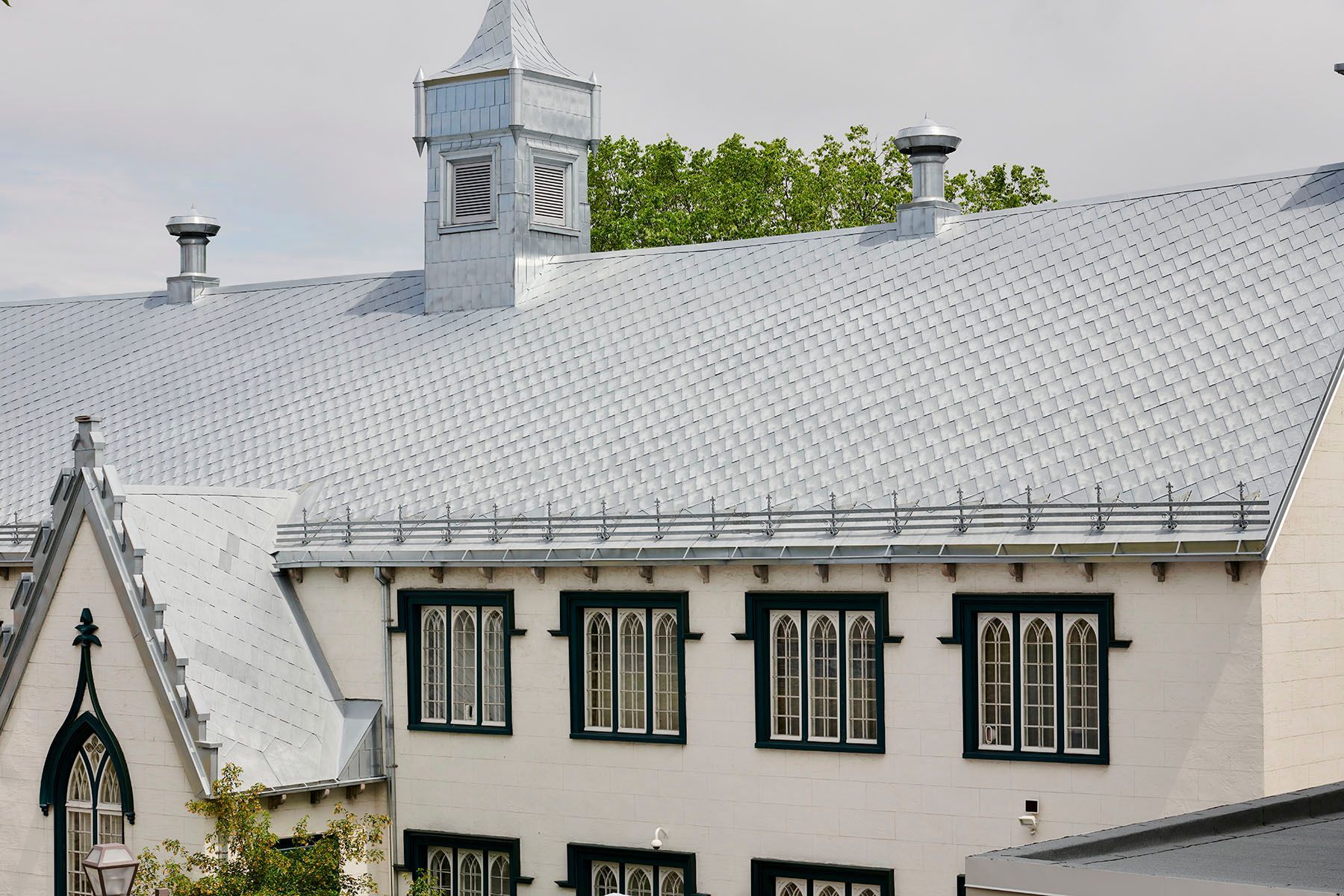 Un bâtiment blanc avec un toit gris et une tour d'horloge au sommet