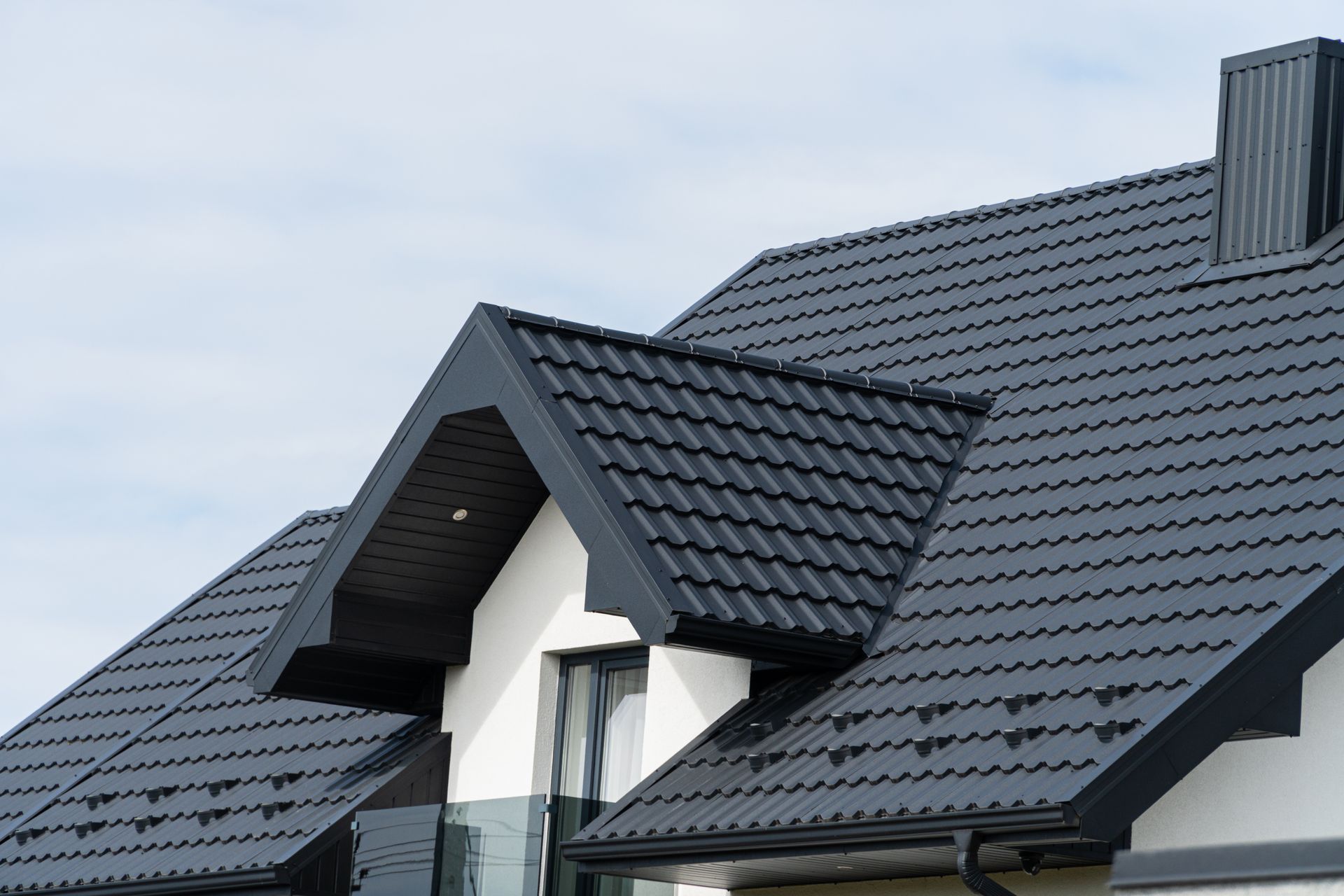 Une maison blanche avec un toit noir et une cheminée