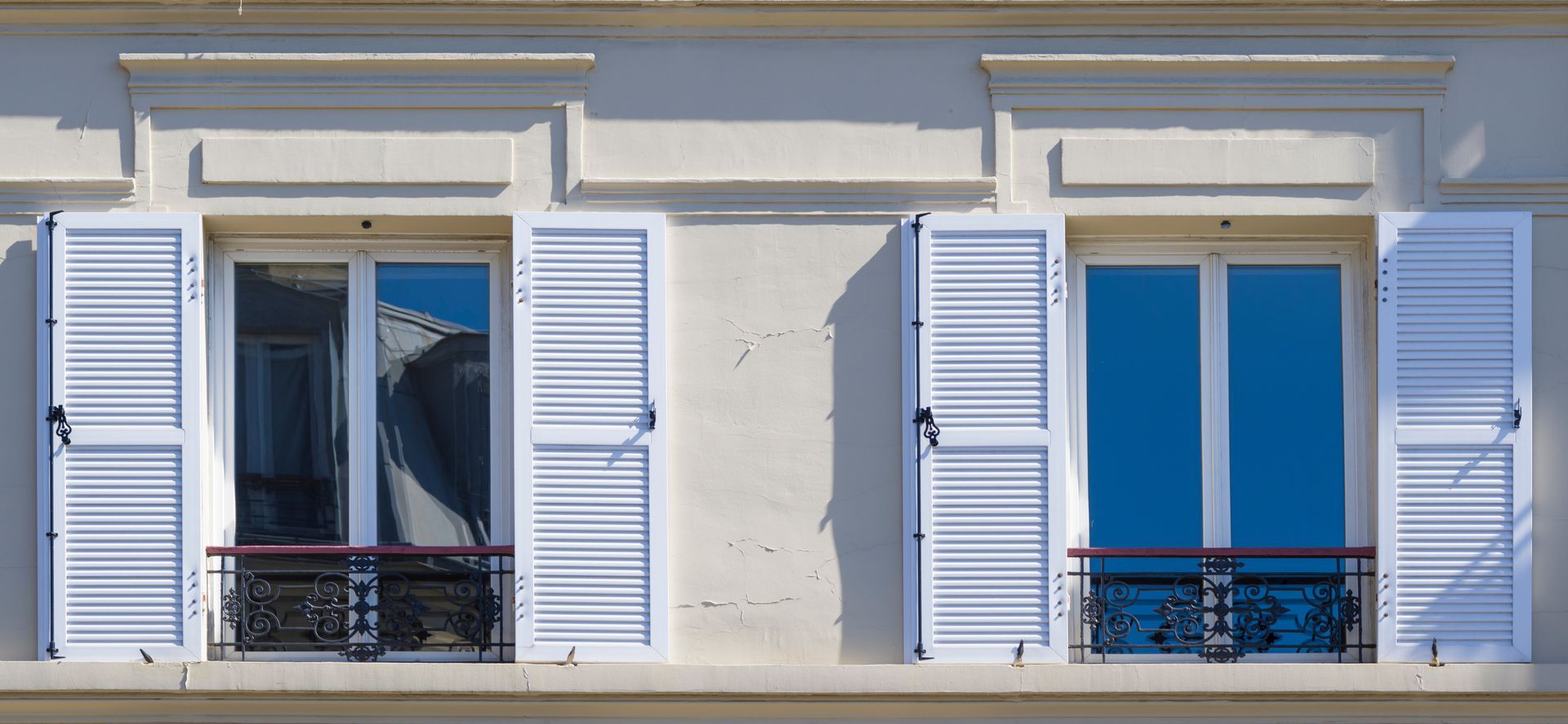 Un immeuble avec des volets blancs aux fenêtres et un balcon.