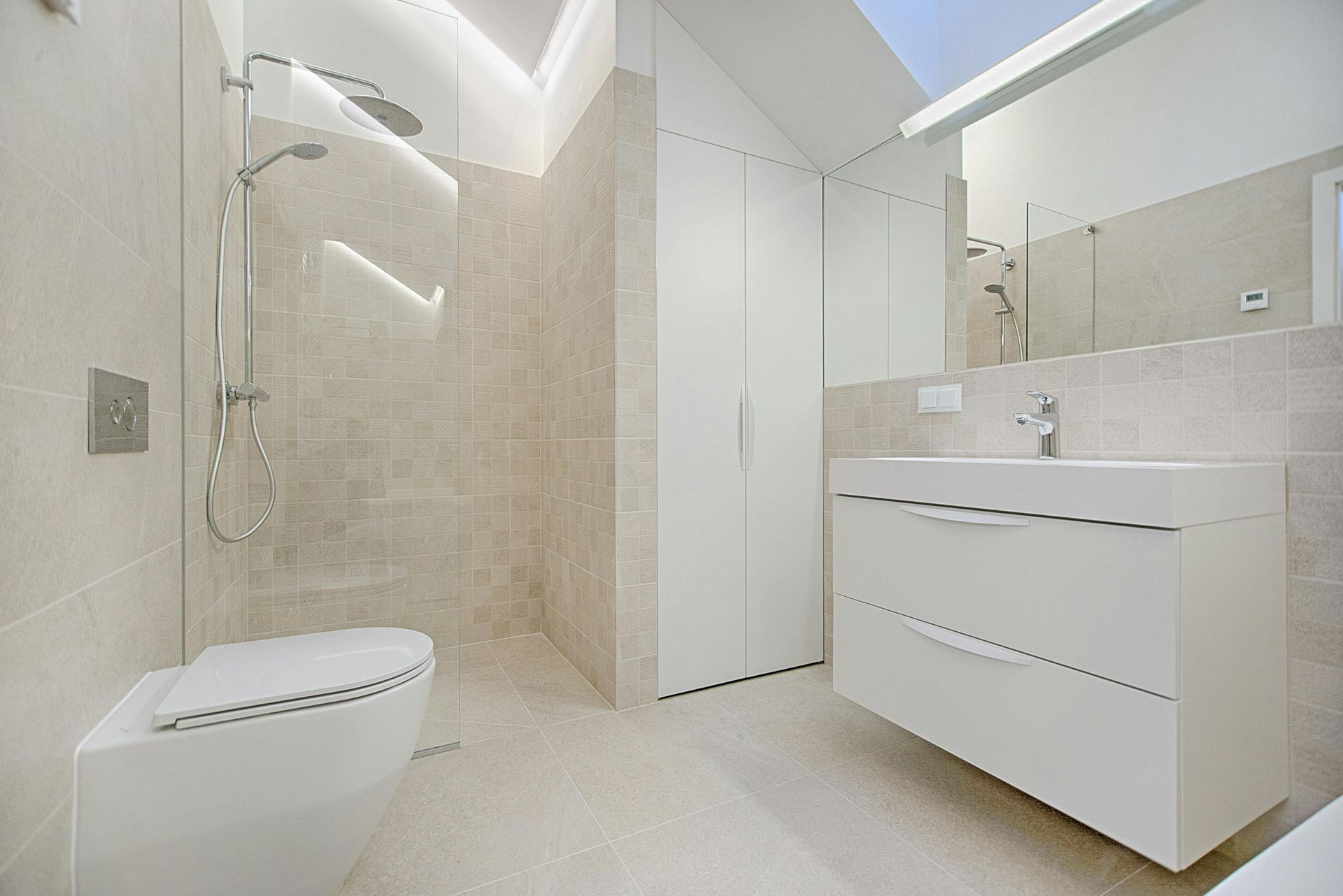 Salle de bains moderne avec équipements blancs, murs carrelés beiges et puits de lumière.