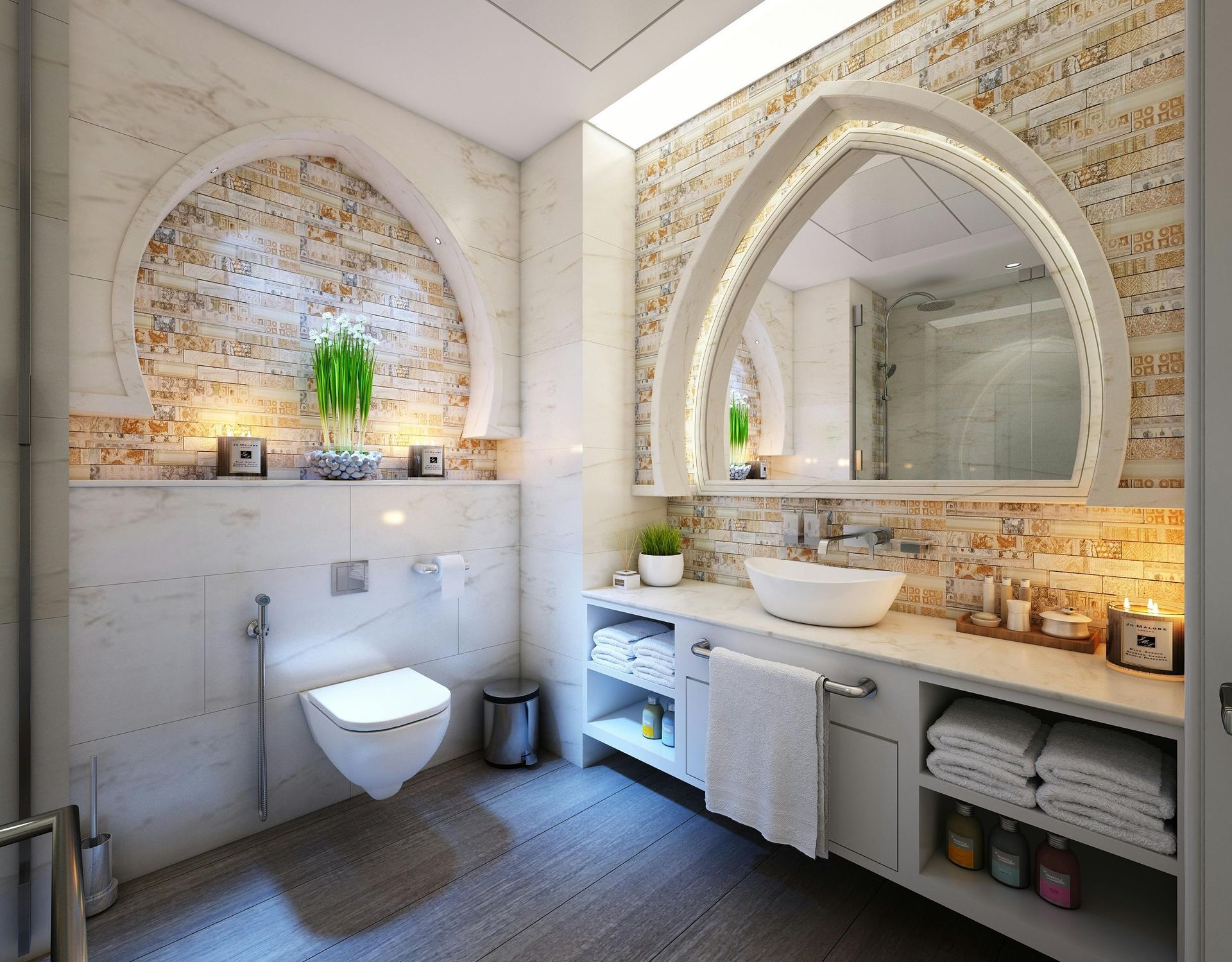 Salle de bains élégante avec miroir arqué, carrelage en mosaïque, toilettes suspendues et meuble-lavabo intégré avec rangements.
