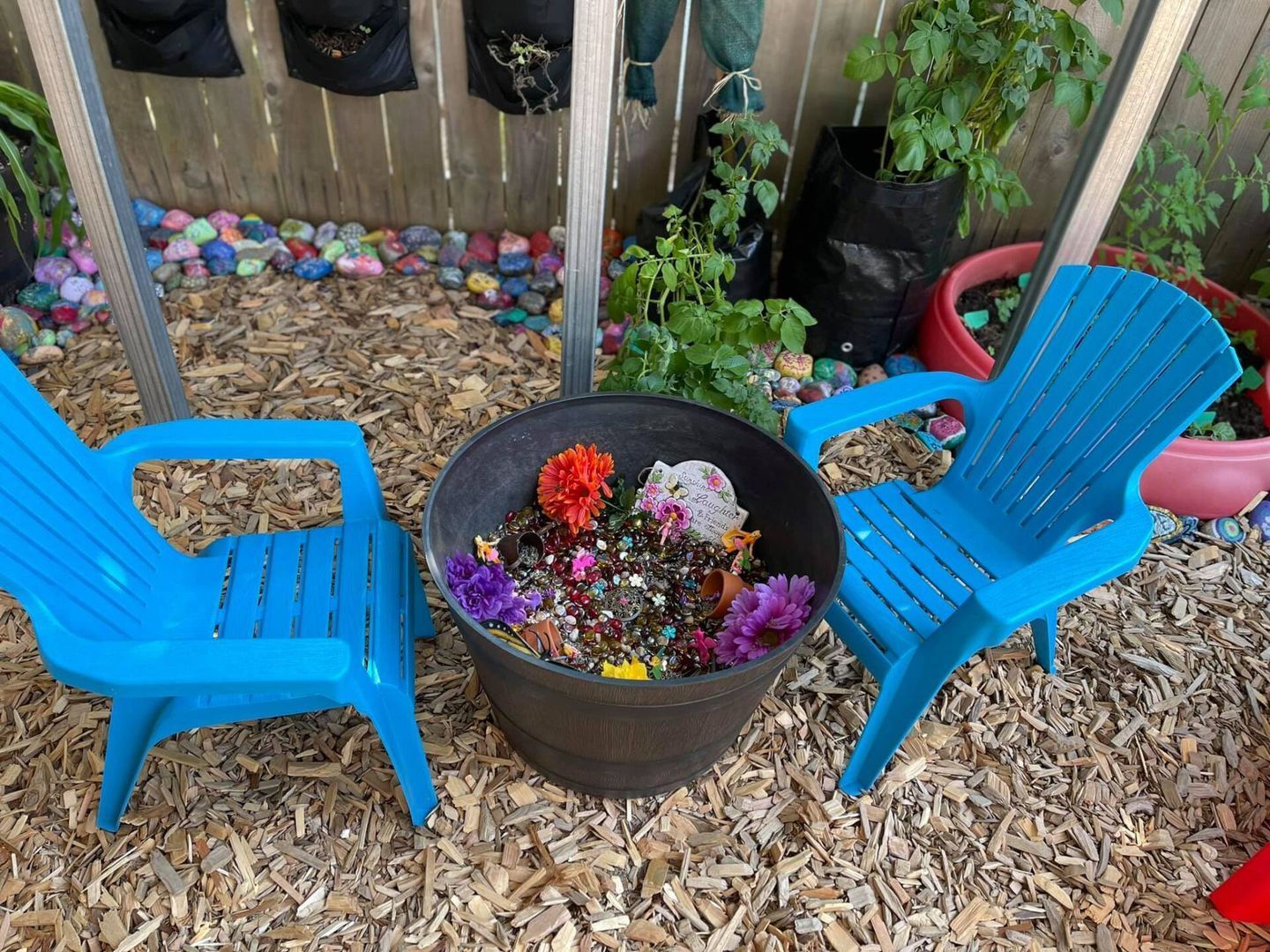 Two blue chairs face a flower pot.