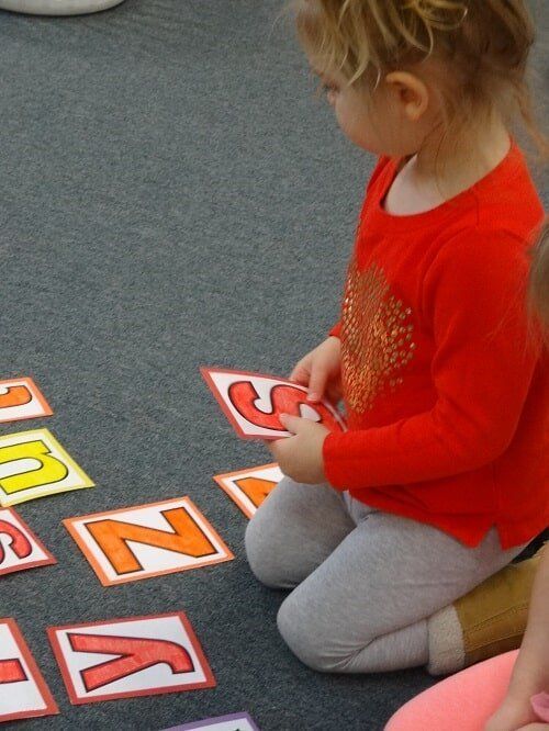 Child with blonde hair in red shirt kneels