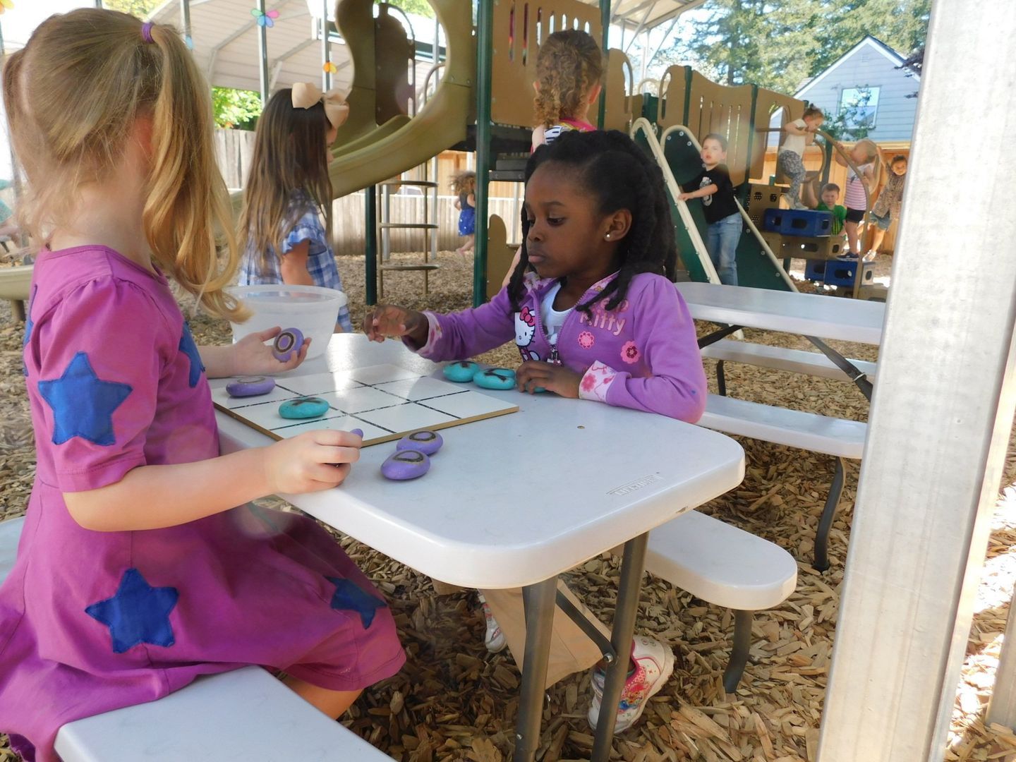Two young girls playing a game at a table outdoors