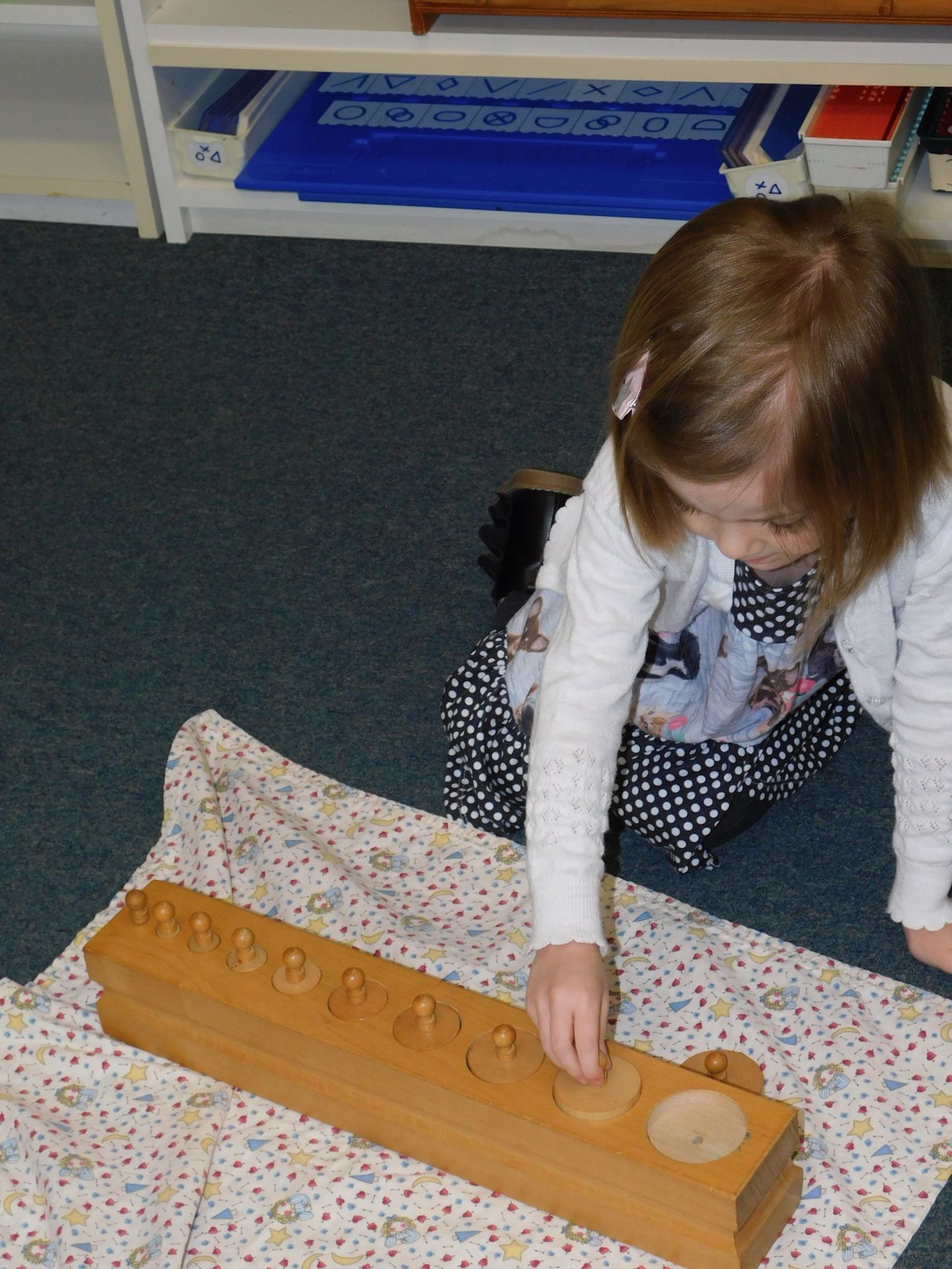 Young girl playing with wooden cylinders at a table