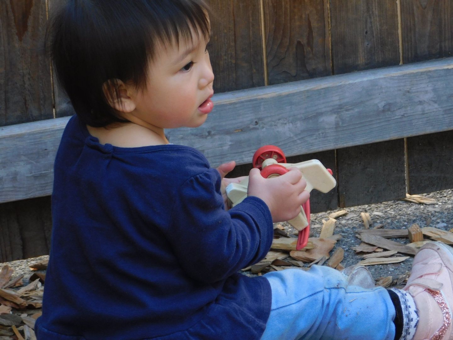 Child sitting, playing with wooden toy airplane