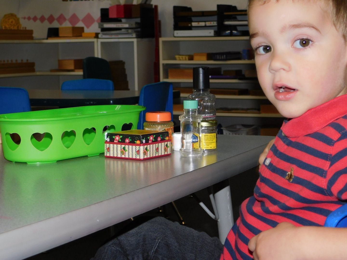Young child at a table with green basket and containers