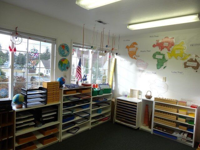 Montessori classroom with shelves, a world map, and windows