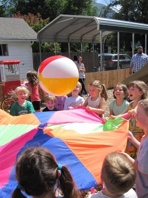 Children playing with a parachute and a beach ball outdoors