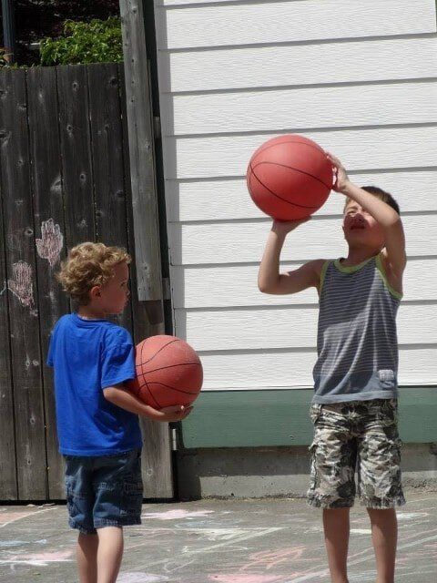 Two boys playing basketball outdoors