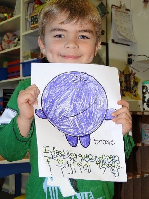 Boy holding drawing of a purple, round, brave character
