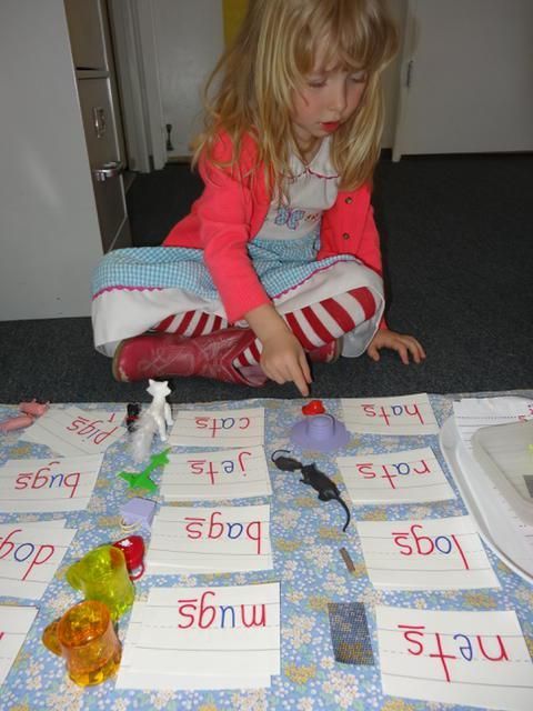 A young girl pointing to a word card on the floor