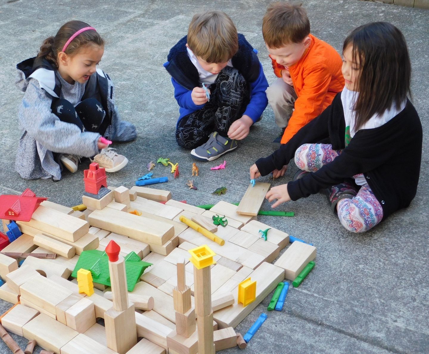 Four children building with wooden blocks outdoors